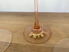 a wine glass sitting on top of a wooden table with the word bridal spelled in gold letters