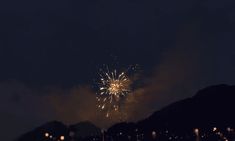 fireworks are lit up in the night sky above a mountain range with lights on it