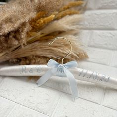 a pair of white hair clips with a blue bow on them sitting next to some dried grass