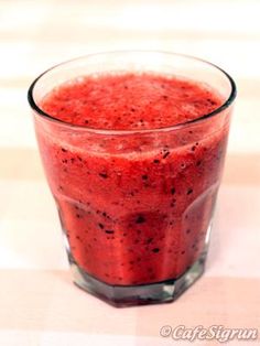 a glass filled with red liquid sitting on top of a table