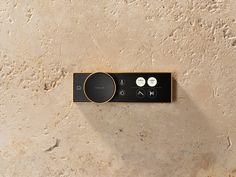 a black and gold control panel on a beige wall with white circles around the buttons