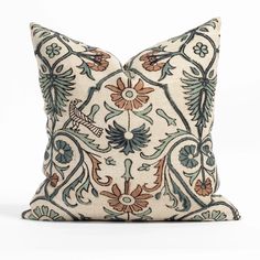 a decorative pillow with blue and orange flowers on it's side, sitting on a white surface