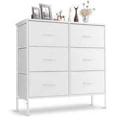 a white dresser with drawers and pictures on top