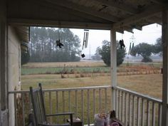 an empty porch with rocking chairs on the front and back sides, overlooking a field