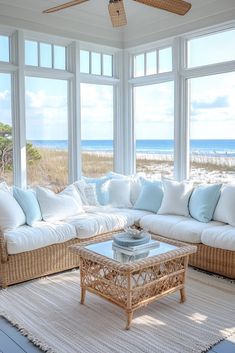 a living room filled with lots of furniture and large windows overlooking the ocean on a sunny day