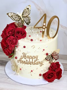 a white cake with red roses and butterflies on top