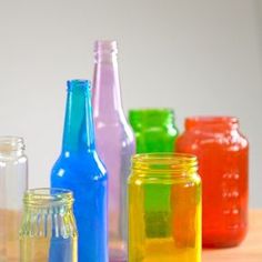 there are many different colored glass bottles on the table