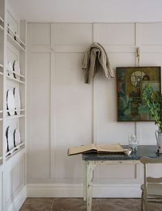 a table and chairs in a room with white walls, bookshelves and pictures on the wall