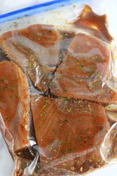 raw fish fillets wrapped in plastic with seasoning on top, ready to be cooked