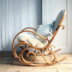 a wooden rocking chair with a blue cushion on the back and white fur trimmings