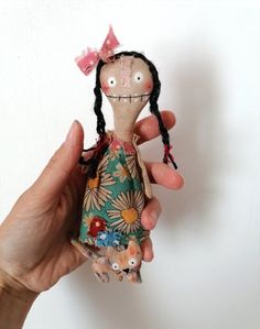 a hand holding a small doll with long hair