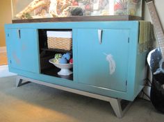 a blue cabinet with some items in it next to a guitar and a wall mounted fish tank