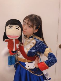 a woman in a blue dress holding onto a stuffed animal doll wearing a red and gold uniform