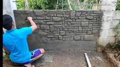 a man sitting on the ground next to a wall made out of bricks and cement