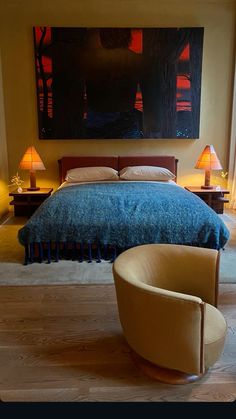 a bedroom with a large painting hanging above the bed and two chairs in front of it