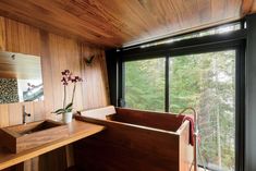 a bathroom with wooden walls and flooring next to a large window overlooking the woods