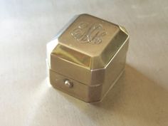 a small metal box with the word monogrammed on it sitting on a table