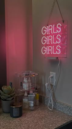 a pink neon sign that says girls's girls on the side of a bathroom counter