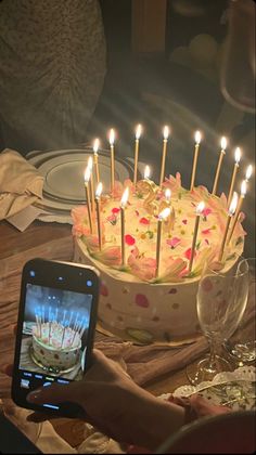 a person taking a photo of a birthday cake with candles on it and someone holding a cell phone