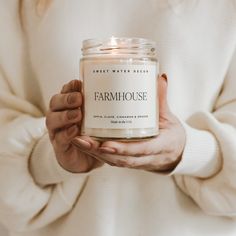 a woman holding a jar of farm house scented candle in her hands with the label on it