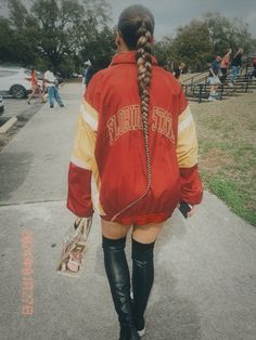 a woman walking down the sidewalk with her back to the camera, wearing a red and yellow jacket