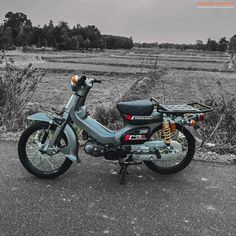 the motorcycle is parked on the side of the road in front of an empty field