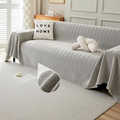 a living room with a couch covered in a gray blanket and pillows on top of it