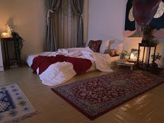 a room with a bed, rug and two candles on the floor next to it