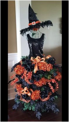 a halloween tree made out of fake pumpkins and black leaves with a witch's hat on top