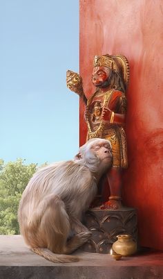 a monkey that is sitting next to a statue