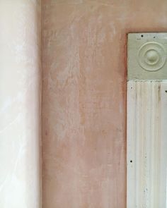 the corner of a room with a mirror and pink paint on it's walls