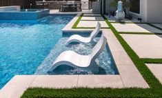 an outdoor swimming pool with artificial grass on the sides and water running down the side