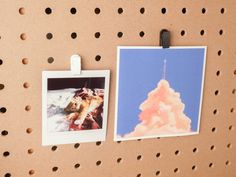 two pictures hang on a pegboard with holes in it and one has a rocket launching