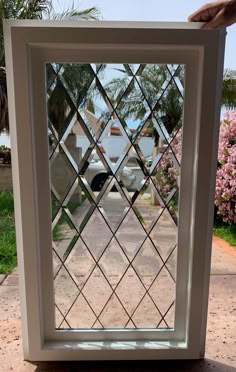 a hand is holding up a window that has been made to look like a diamond pattern