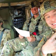 three soldiers sitting in the back of a vehicle and one is holding a piece of paper