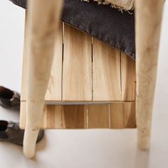 a pair of black shoes sitting on top of a wooden chair next to a cushion