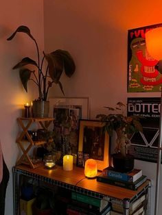 a table with books and candles on it in front of a wall that has posters