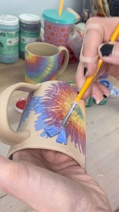 someone is painting a flower on a coffee mug