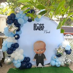 an image of a baby in a suit surrounded by blue and white balloon garlands