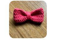 a pink crocheted bow tie sitting on top of a wooden table