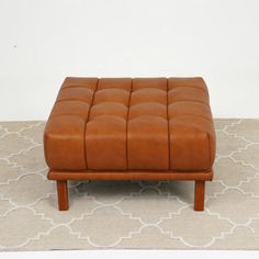 a brown leather ottoman sitting on top of a rug