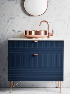 an image of a bathroom vanity with blue drawers and gold faucet on it