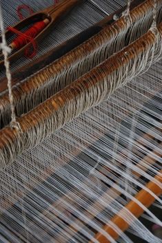 an old weaving machine with yarn on it's sides and two orange needles in the middle