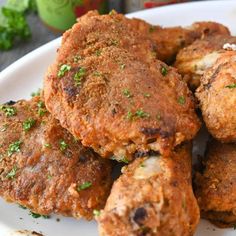 some fried food on a white plate with garnishes and seasoning sprinkles