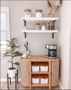 a shelf with some cups on top of it and a potted plant in the corner