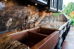 a kitchen sink with two faucets in it and granite counter tops on the side