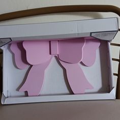 an open box with two pink bows on the front and one bow on the back