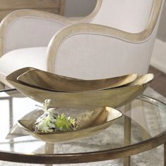 a glass table topped with two metal bowls filled with succulents and plants