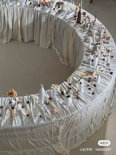 the table is covered with white cloths and candles are arranged in a circular pattern