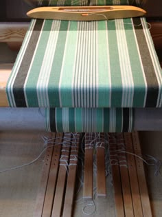 a green and white striped bench with wooden slats